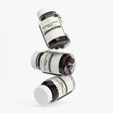 Three dark supplement bottles with white caps and cream labels reading BRIDGE Mushroom Cell Complex, arranged in a floating diagonal composition on a light gray background.